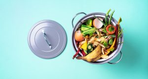 Garbage sorting. Organic food waste from vegetable ready for recycling in compost bin on blue backgrond. Top view. Sustainable and zero waste living. Environmentally responsible behavior, ecology concept.